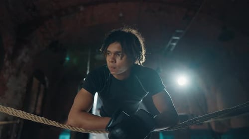 Boxer Leaning on Ropes in Boxing Ring
