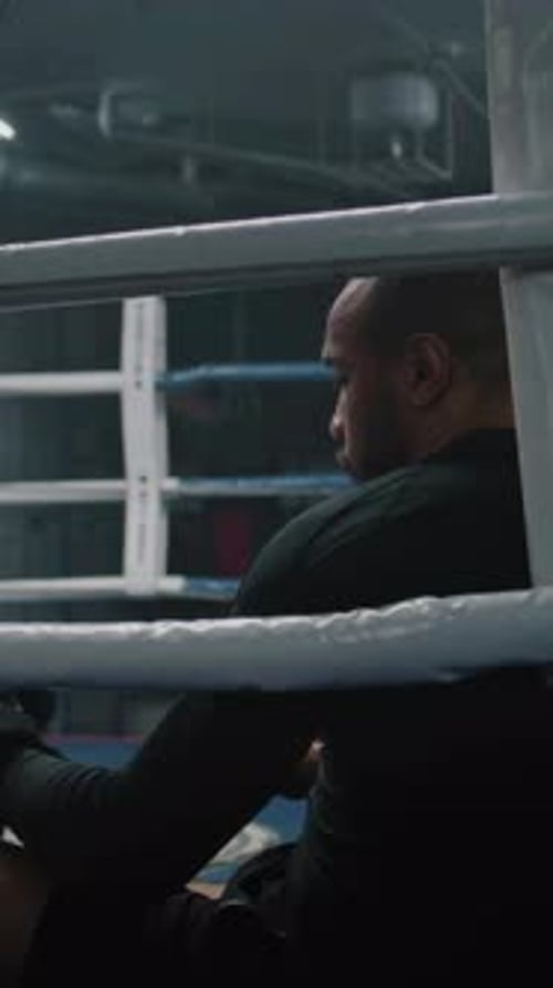 Exhausted African American Fighter Sits Down in Ring Corner