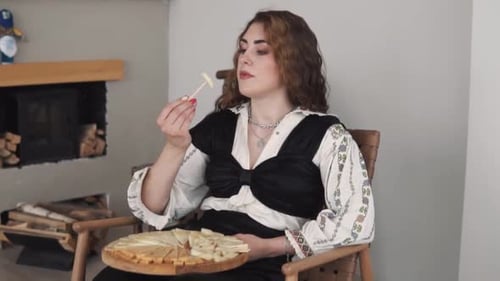 portrait depicts a young, beautiful woman in embroidered authentic Ukrainian attire eating a cheese