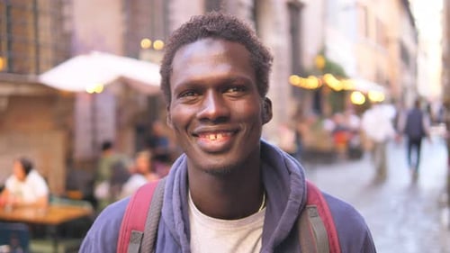 positivity, optimism – serious black man on the street looks at the camera smiling