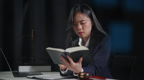 Close up of gavel hammer and lawyer's hands is reading a book table in the office.