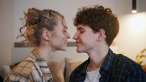 Couple Sharing a Kiss While Sitting Close Together in a Cozy Indoor Setting During a Relaxed Moment