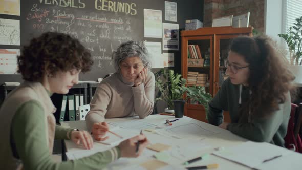 Teacher and Two Students Discussing Text on Papers during English ...