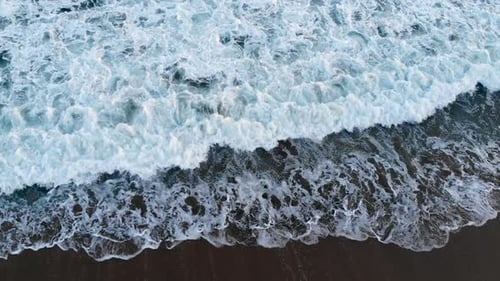Top-Down-Aufnahme wunderschöner blauer Wellen, die in Seal Beach, CA, auf das Ufer krachen.