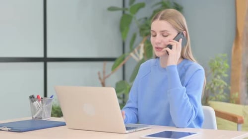 Young Woman Talking on Cell Phone at Desk