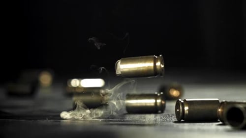 Smoking Bullet Shells Falling onto Surface in Slow Motion