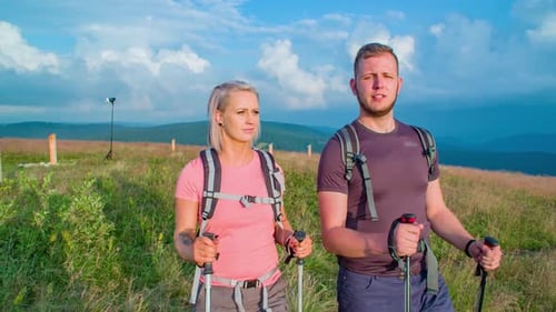 Slow motion shot of two hikers walking towards camera at the top of a hill