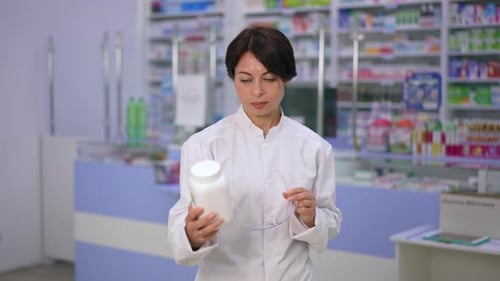 Female Pharmacist Examining Medicine in Pharmacy Setting
