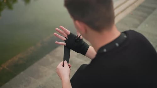 Man Wrapping Hands for Boxing Training by Water
