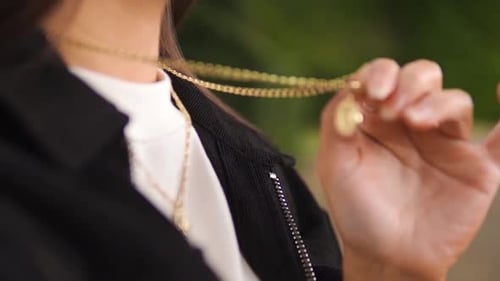 close up shot of a young caucasian woman touching her golden necklace jewellery wearing silver rings