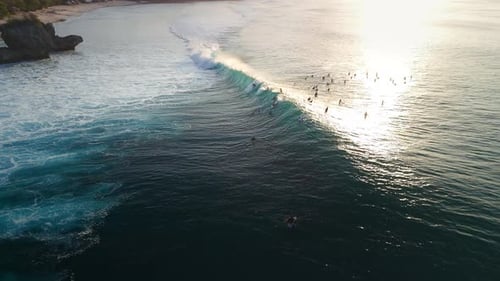Surfing on Perfect Swell Waves Ideal Wave with Surfers on Line Up in Ocean at Bali with Sunset