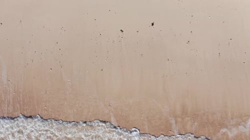 Aerial view waves break on white sand beach at sunset. Sea waves on the beautiful beach aerial view