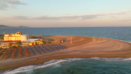 Mediterranean beach with colorful umbrellas and calm waves breaking on shore at sunrise