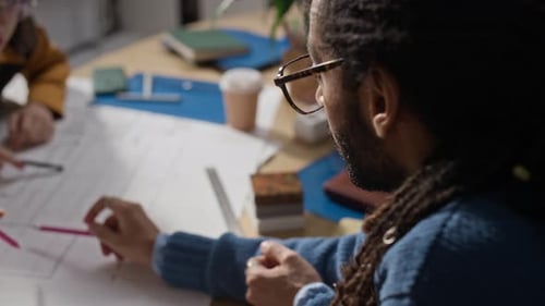 Multiethnic Architects Team Discussing Paper Building Plan at Workplace