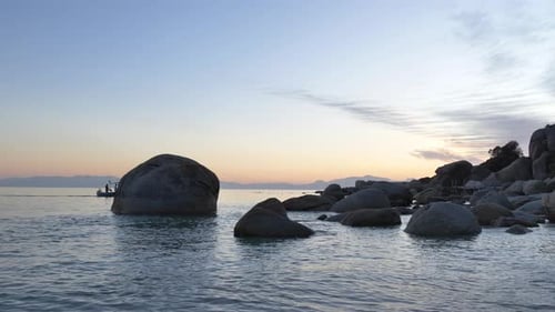 Boat on Calm Water at Sunset with Rocky Coastline