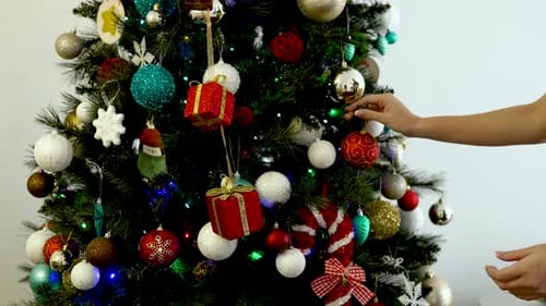 Hands Placing Decorations on the Christmas Tree - Close Up