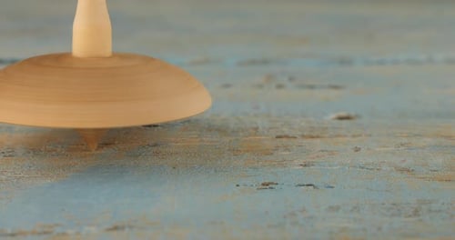 Toy Wooden Spinning Top Spins on Blue Surface