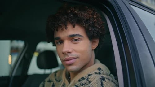 Man Sits in Car Looking at Camera
