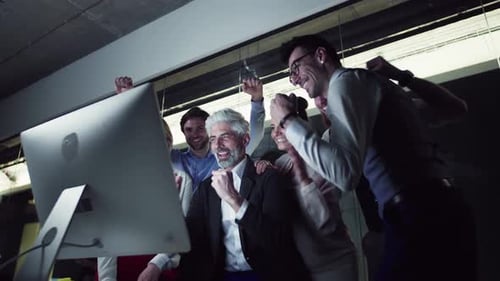 Equipe de negócios animada reage a notícias positivas no computador em um escritório moderno