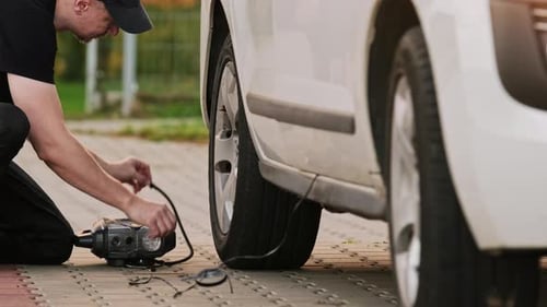 Man Inflates Car Tire with Electric Pump