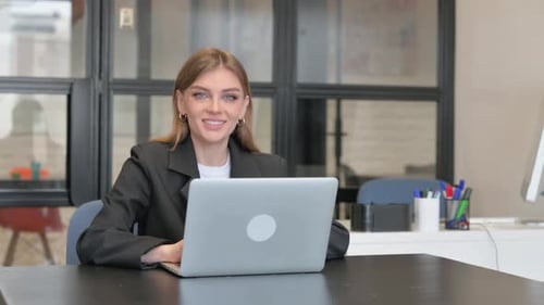 Young Businesswoman Smiling at Camera while Working on Laptop in Office
