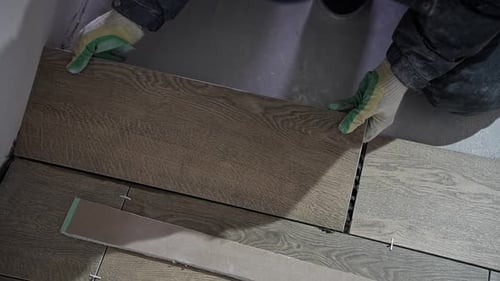 Worker Installing Wood Patterned Tiles Indoors