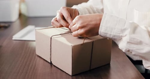 Tying Brown String Around a Cardboard Box Package