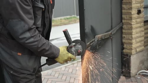 Man Cuts Metal Gate with Power Tool Outdoors