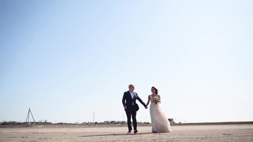 Lovely Bride and Groom Holding Hands Walking Together Outside the City Attractive Man in Suit Woman