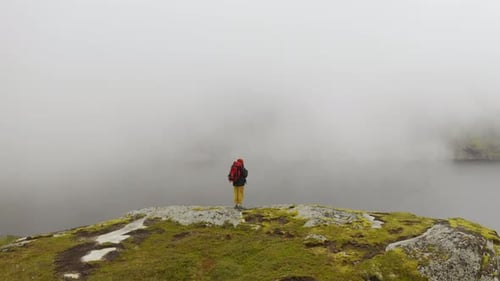 Attractive Girl in Trekking Clothes with Stands on Top of a Mountain Range and Looks Around High in