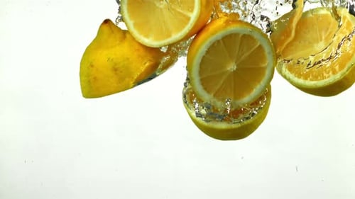 Vibrant Lemon Slices Falling into Water with Bubbles