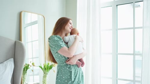 Mother Cradling Infant Daughter in Bedroom Light