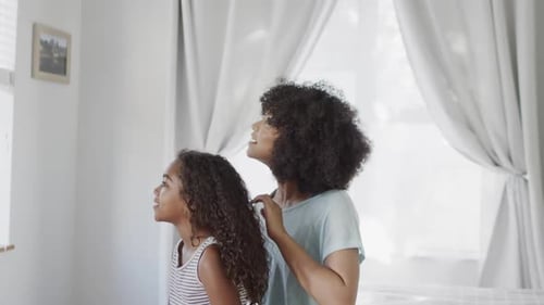 Woman Brushing Child's Hair in Bright Home