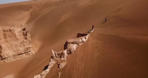 fly over a big rock cliff surrounded by desert sand dune in lut geopark natural heritage in UNESCO w