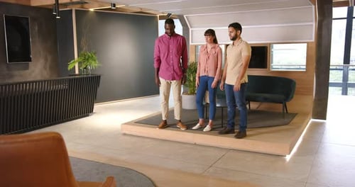 Discussing work, three diverse colleagues standing together in modern office