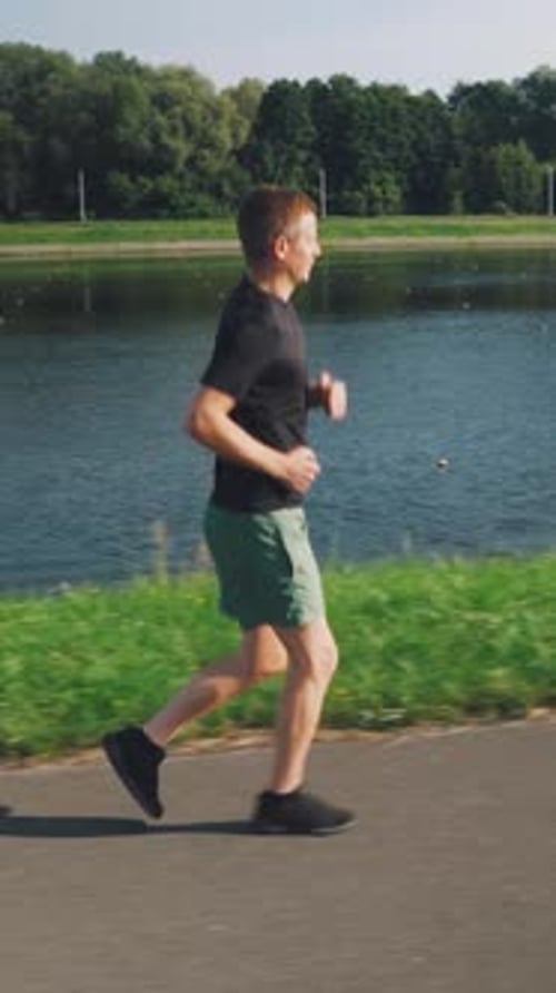 Man Jogging Along Riverside Path on Sunny Day