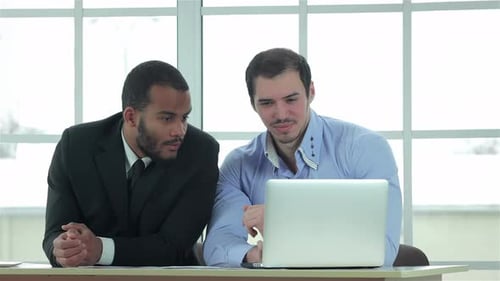 Business Men Discussing Information on Laptop in Office