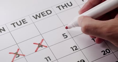 Markieren des Kalenderdatums mit rotem Stift zur Erinnerung an die Frist