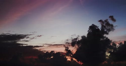 Dark and crimson clouds moving and pink reflections on the blue sky after sunset. Time Lapse