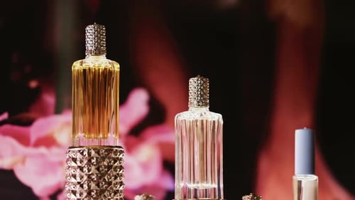 Élégants flacons de parfum en verre avec détails dorés et en cristal, décorés avec un éclairage doux et des fleurs