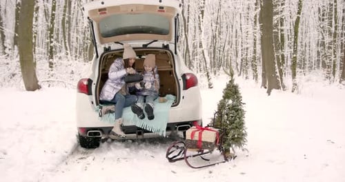 Mother and Daughter Sitting in a Car Truck in Winter Forest