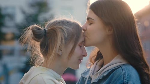 Two Lesbian Woman Standing in the City Centre the Woman with Short Hair Kisses Her Partner in the