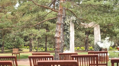 Weeding Arch Decorated with Pastel Faded Flowers and Wooden Chairs in the Park Slow Motion Shot