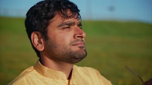 Indian Groom Removing Glasses and Enjoying Sunlight in a Green Field
