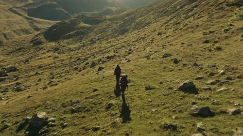 Cinematic Hiker Walking Alone on a Green Mountain Landscape at Sunset