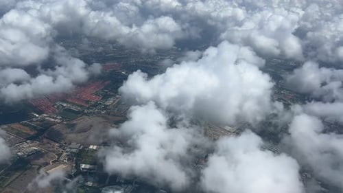 An aerial view of the clouds and cityscape below the clouds.