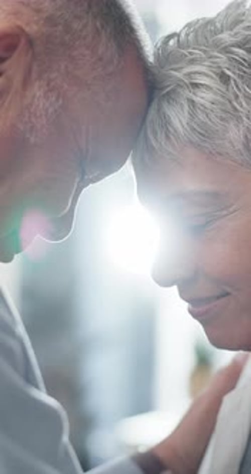Affectionate Senior Couple Touching Foreheads Indoors
