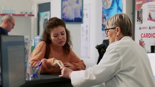 Woman Discusses Prescription with Pharmacist at Pharmacy