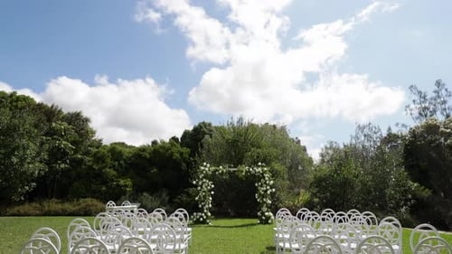 Outdoor Wedding Ceremony With Floral Arch and Chairs