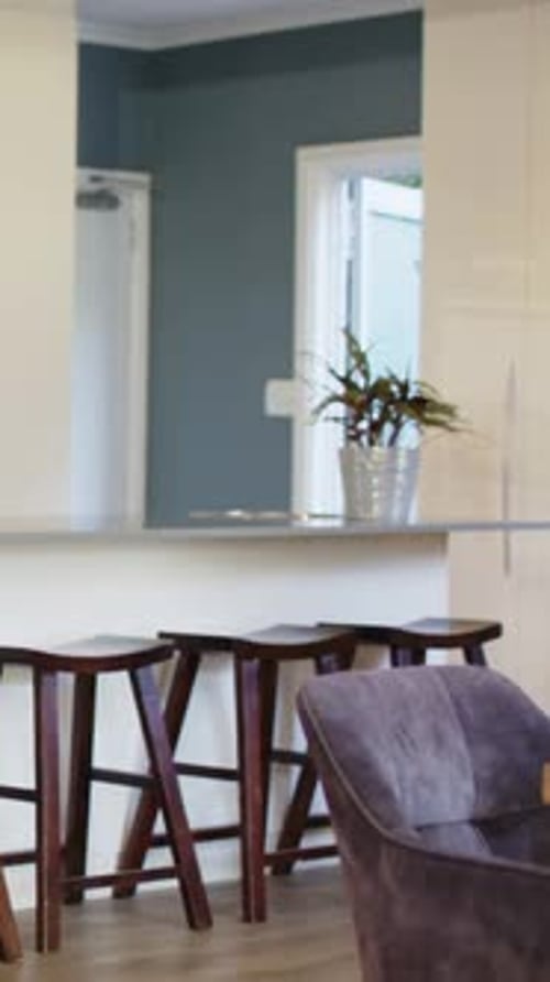Vertical video: Camera starting, panning right across kitchen, revealing bar with 3 stools plant